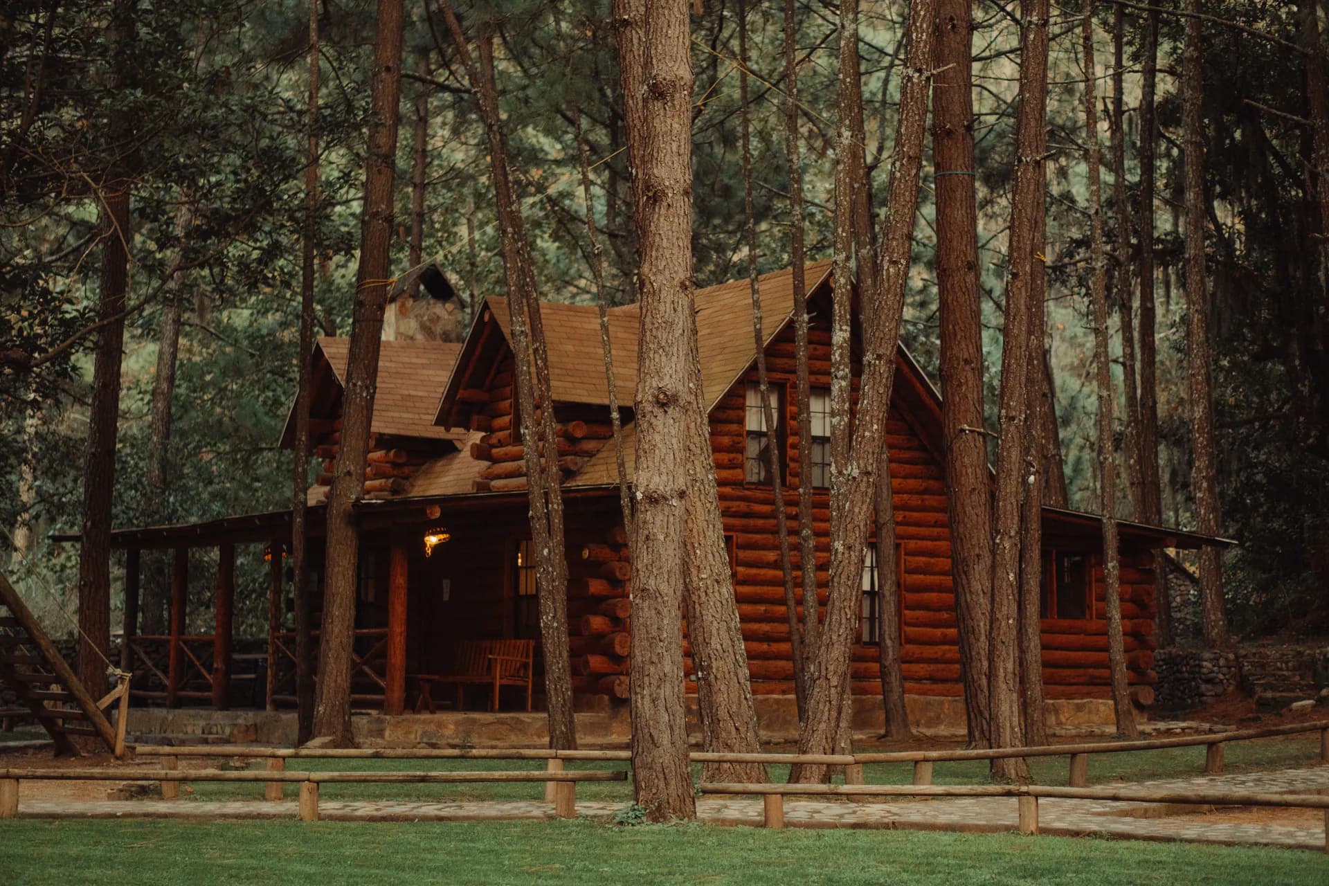 Imagen de ejemplo de BookNoFees: cabaña de madera con terraza cubierta entre altos árboles del bosque