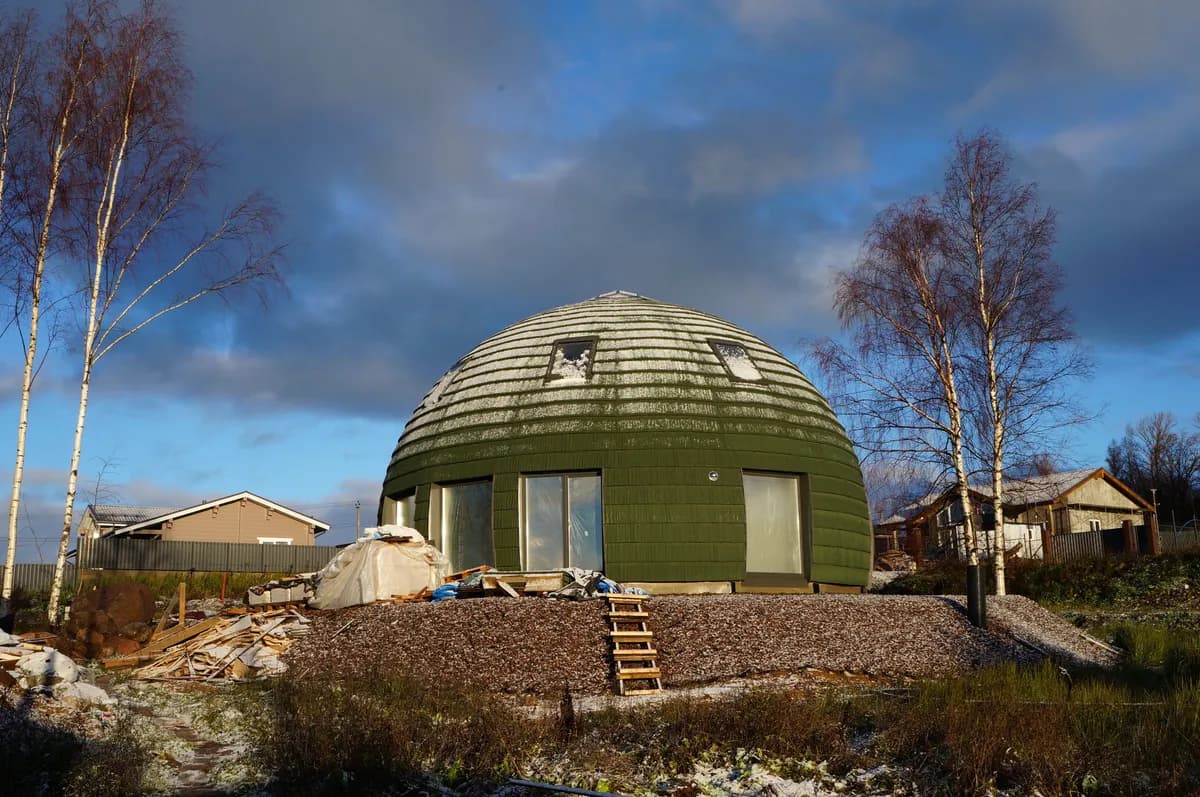 Imagen de ejemplo de BookNoFees: Casa con cúpula verde bajo un cielo azul en un terreno ajardinado