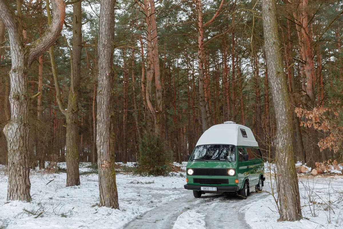 Imagen de ejemplo de BookNoFees: una furgoneta de camping verde con techo alto en un bosque nevado
