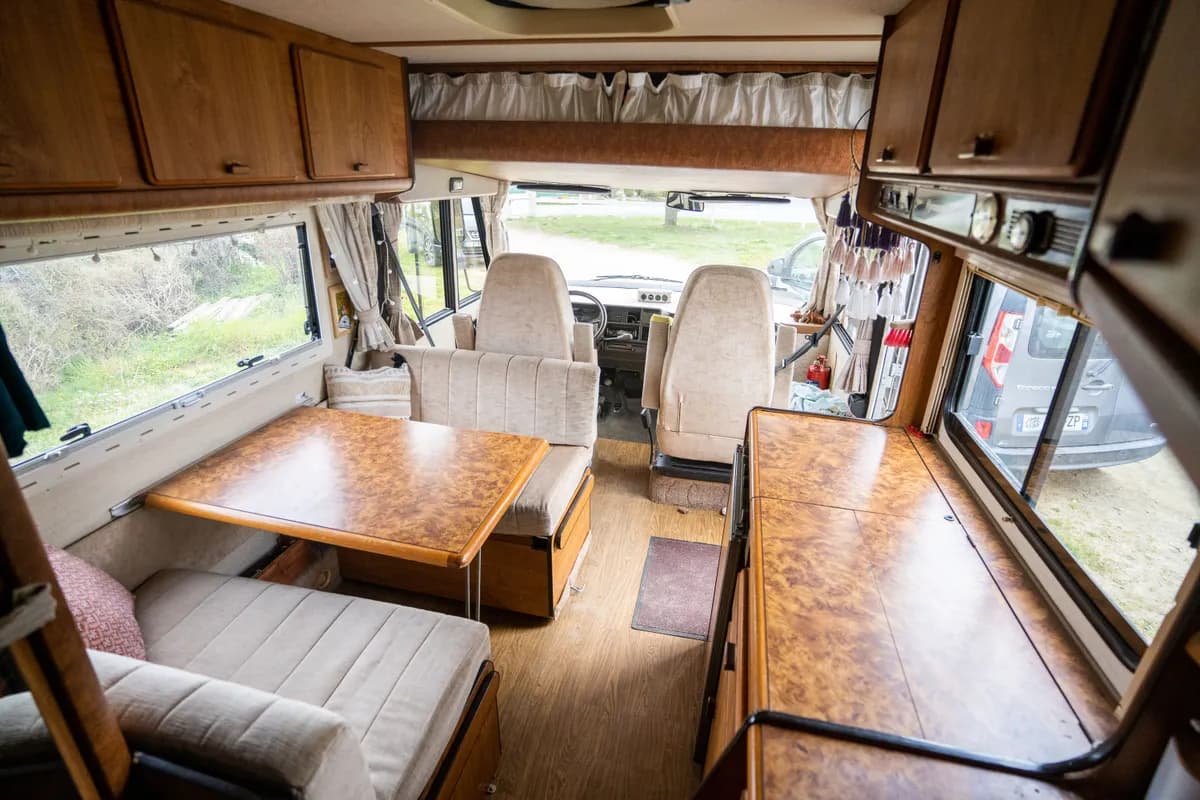 Imagen de ejemplo de BookNoFees: interior de una autocaravana con cocina, mesa y bancos tapizados