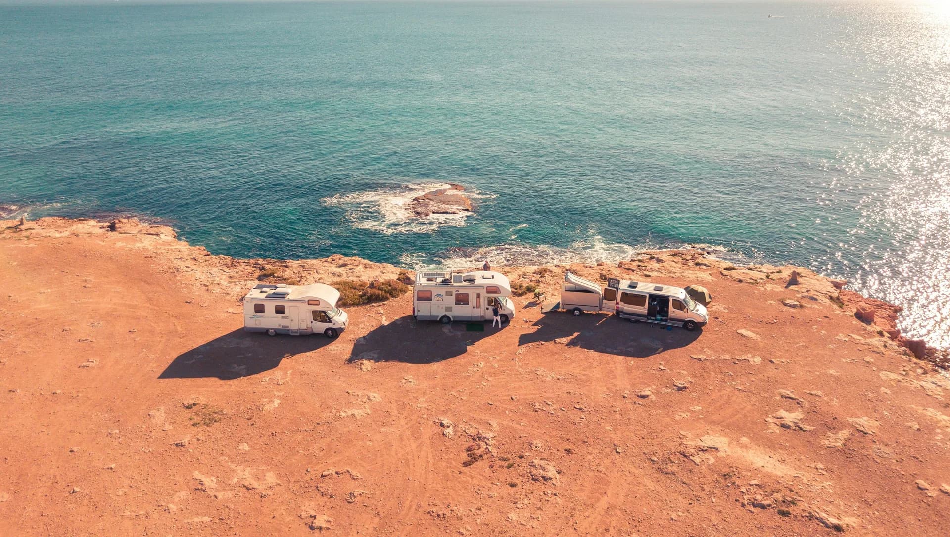 Imagen de ejemplo de BookNoFees: tres autocaravanas en un aparcamiento soleado junto al mar
