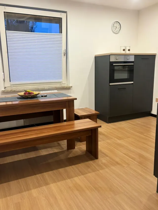 BookNoFees: alojamiento de vacaciones en Bodenwerder – Cocina con mesa de comedor de madera, banco, horno empotrado y ventana con persiana