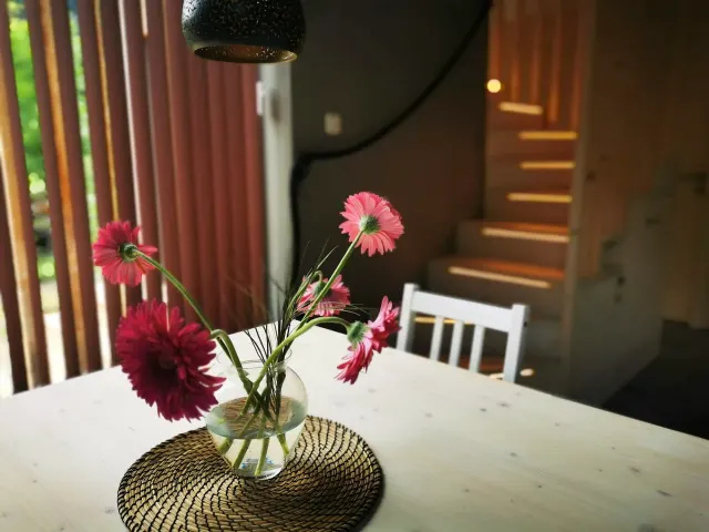 BookNoFees: alojamiento de vacaciones en Hieflau, Estiria, Austria – Sala de comer con una mesa blanca, un jarrón con flores rosas y una escalera de madera