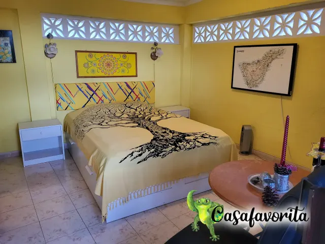 BookNoFees: alojamiento de vacaciones en Buen Paso, Tenerife, España – Habitación con cama doble, colcha con motivos de árboles y ventanas decorativas de bloques de concreto